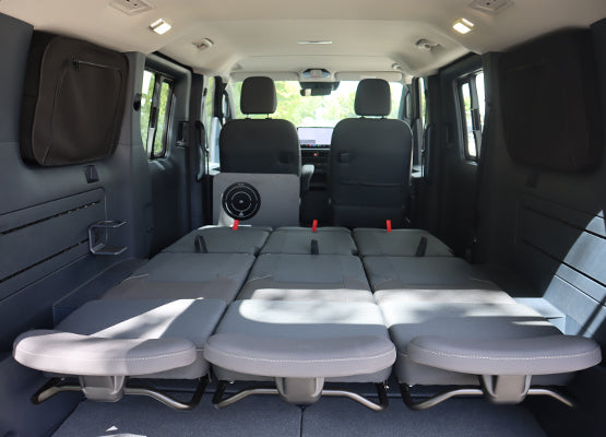 Kia PV5 ComfortLine avec sièges Schnierle RelaX en position couchage : photo fabricant illustrative